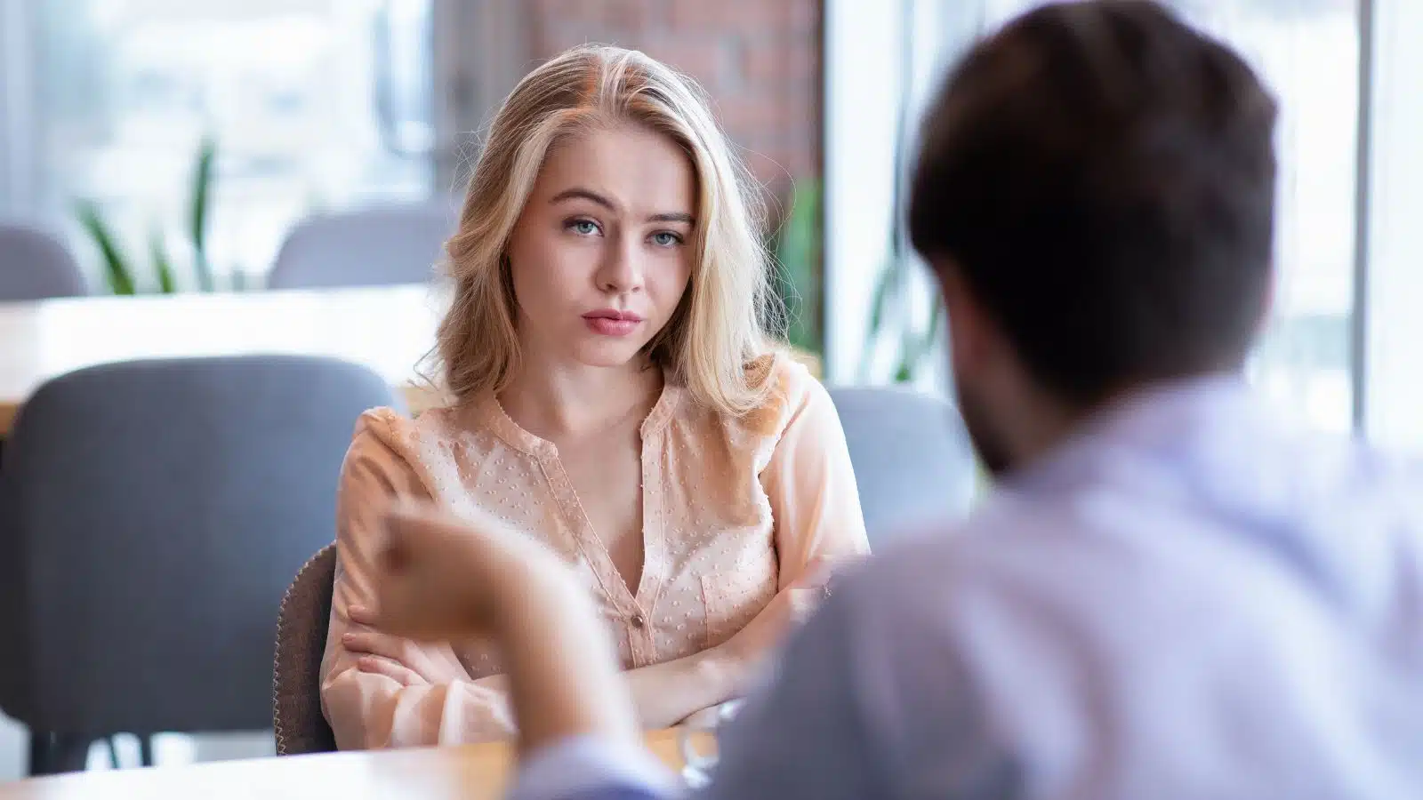 A woman looks at her date, unimpressed and annoyed by what he is saying.