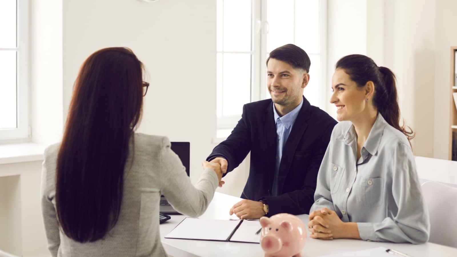 A couple shakes hands with a banker while applying for a personal loan.