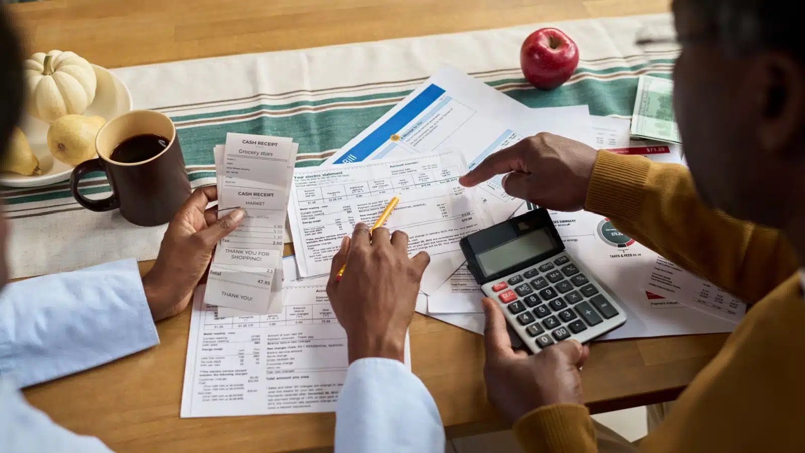 A couple has financial statements and bills spread across the table to review their entire financial life.