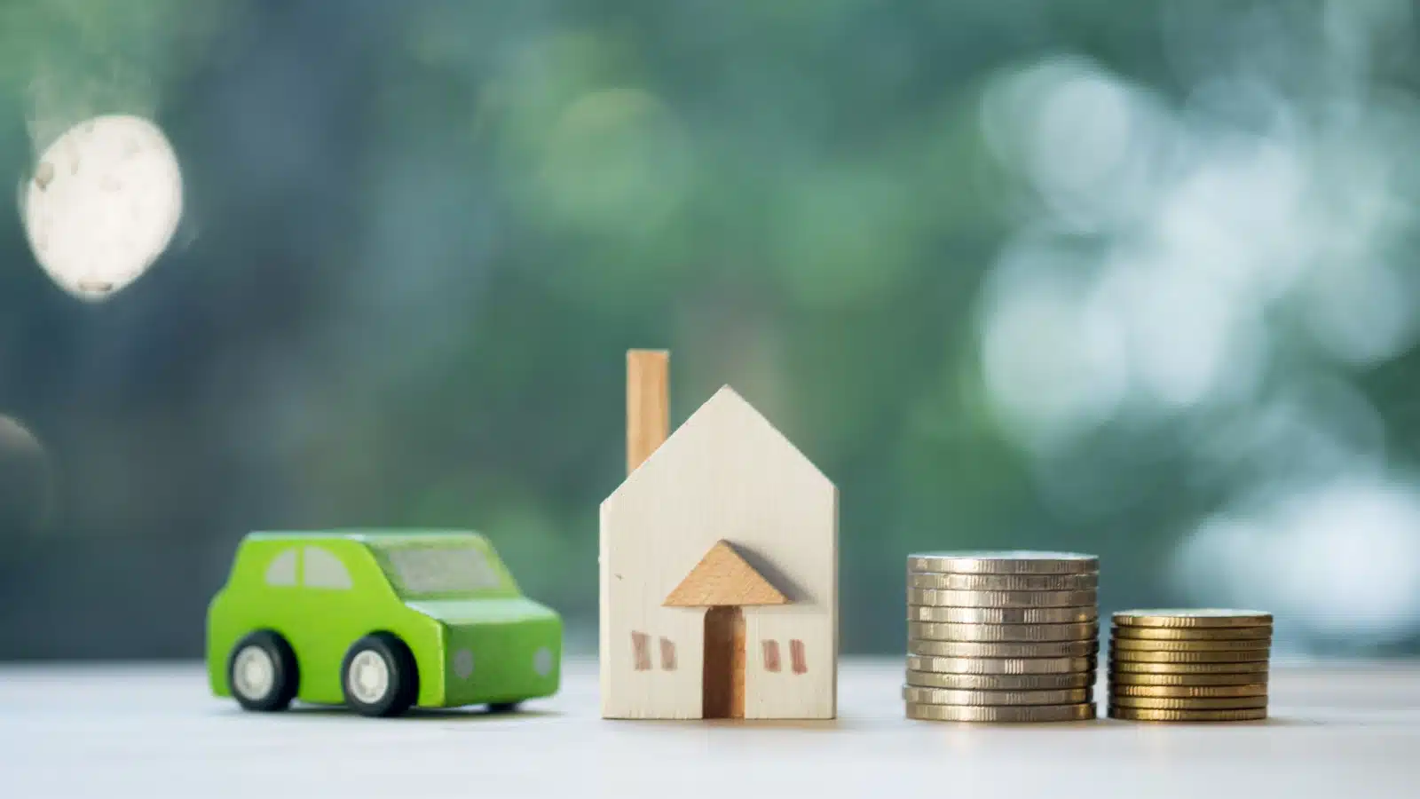 Concept photo representing collateral for a loan. A tiny model car and home sit on a table next to a pile of change.