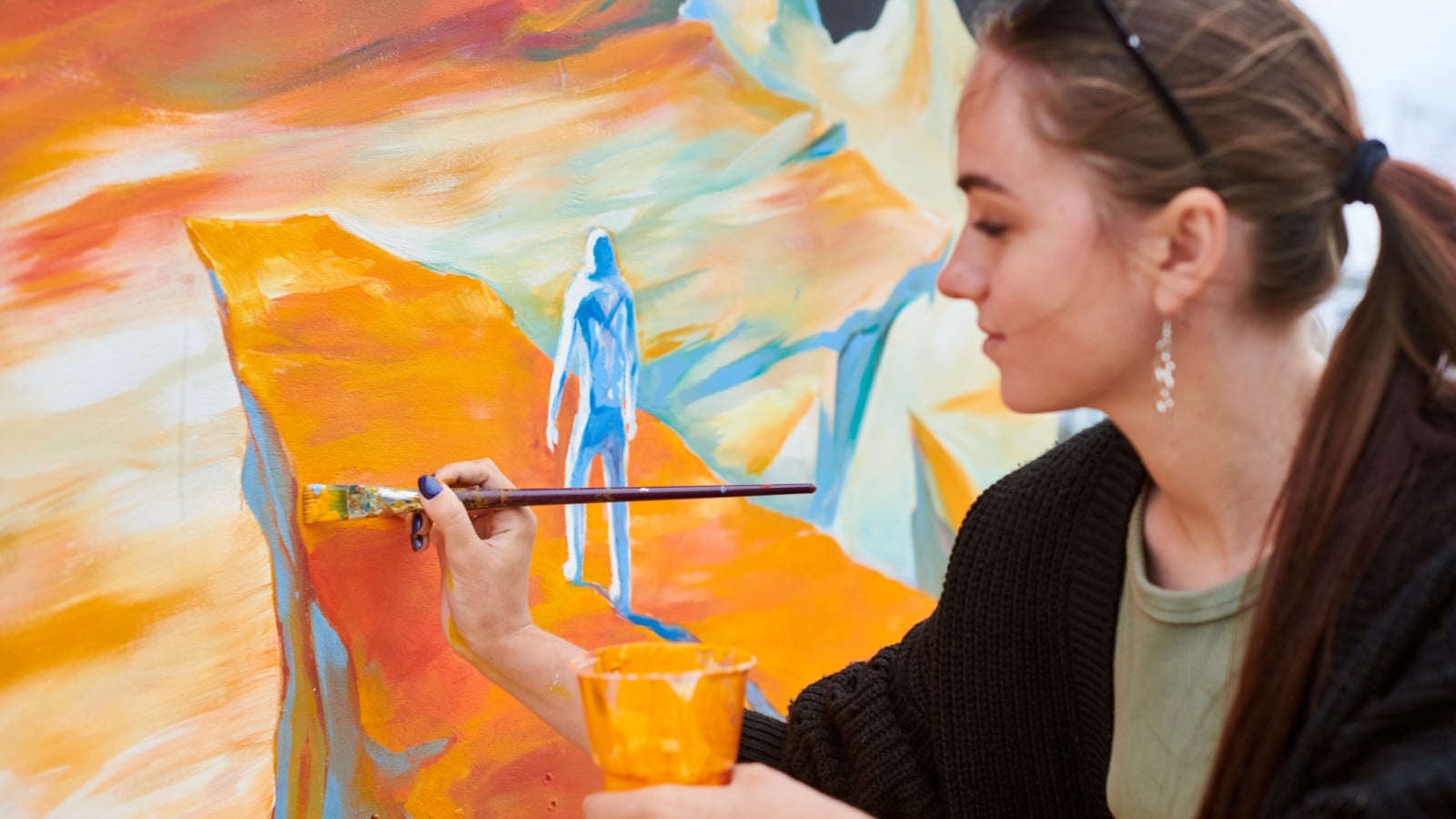 A woman uses a variety of orange shades in her painting.