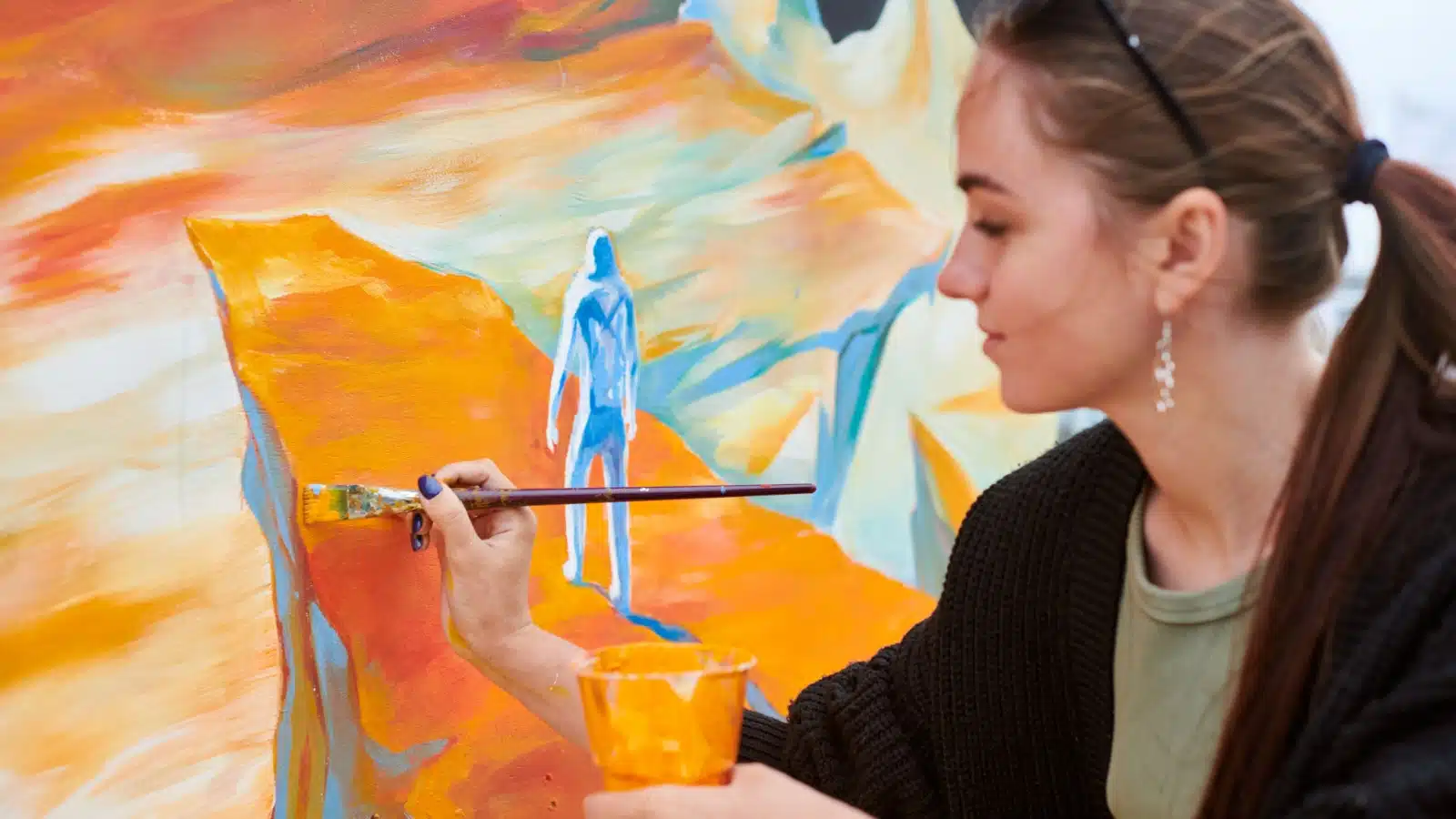 A woman uses a variety of orange shades in her painting.