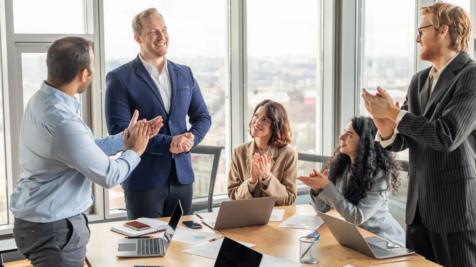 A group of colleagues applauding a coworker in a show of respect and gratitude.