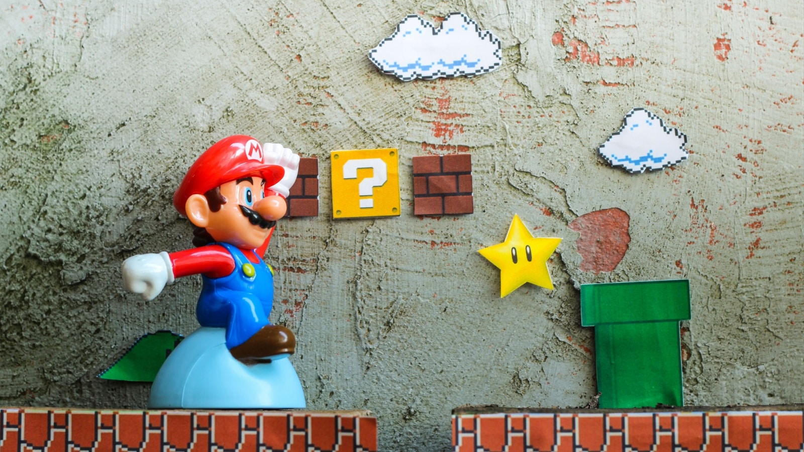 Cut out artwork showcasing Super Mario bros. The Mario figure looks 3D, but he's exploring a flat side scroll world from the original games.