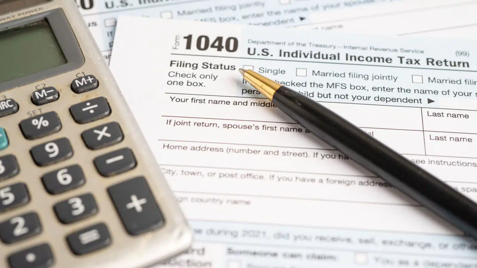 An IRS 1040 tax form next to a calculator.