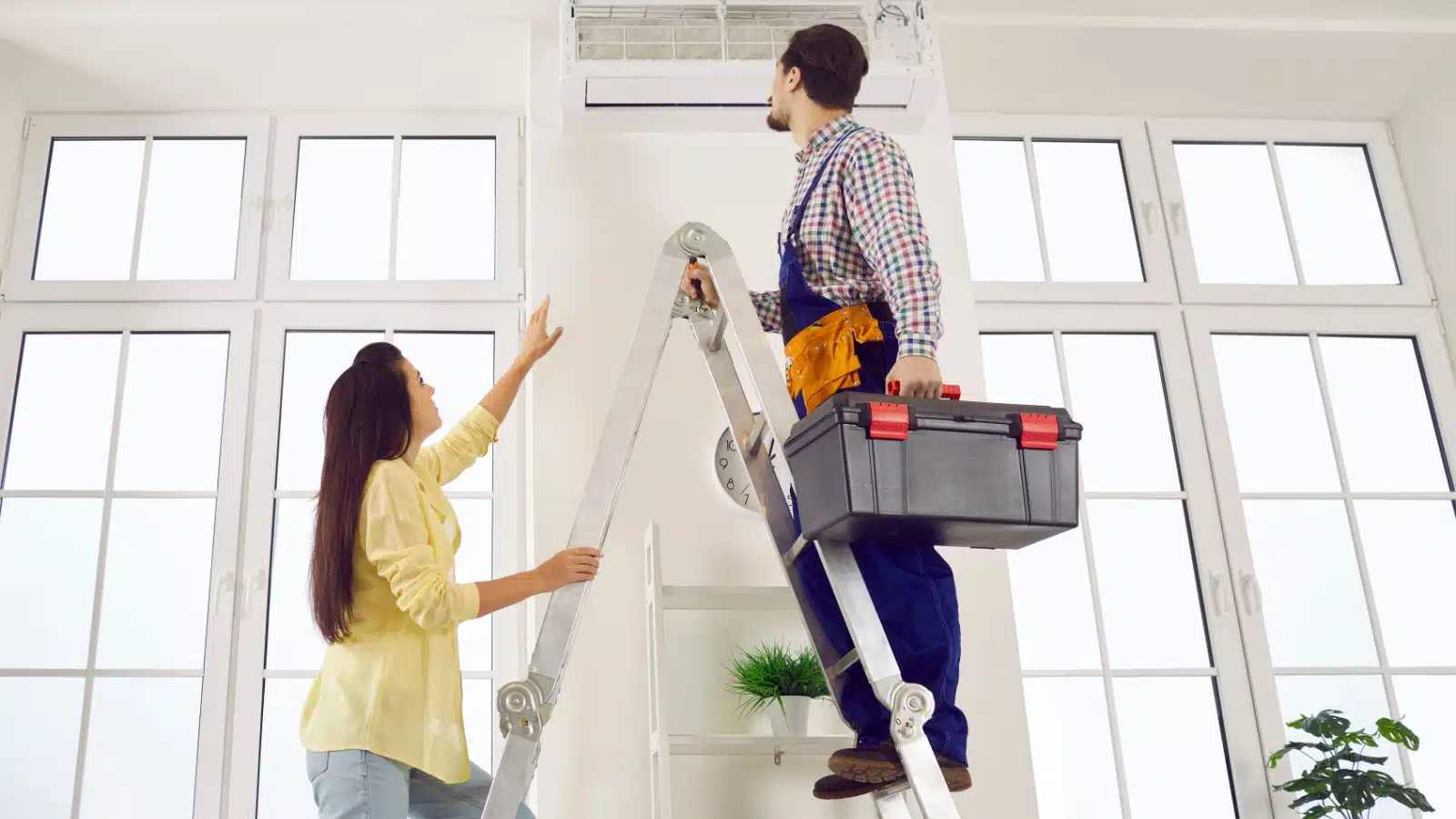 A technician repairing an HVAC unit inside someone's house.
