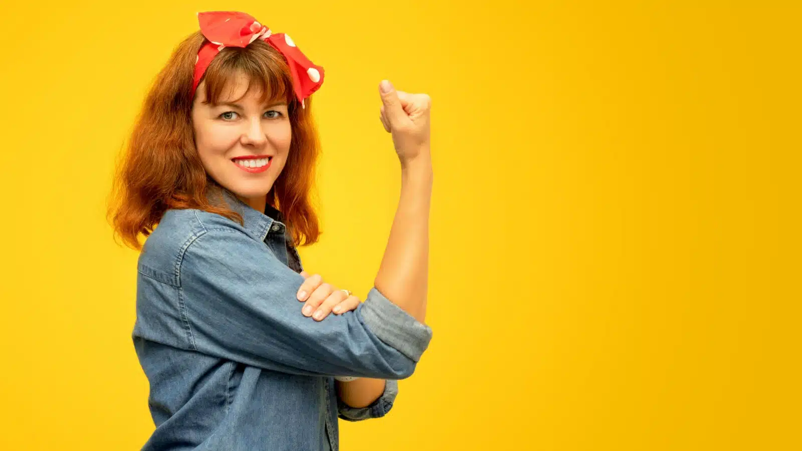 A woman paying homage to Rosie the Riveter. Her pose indicates a sense of confidence and self-belief.