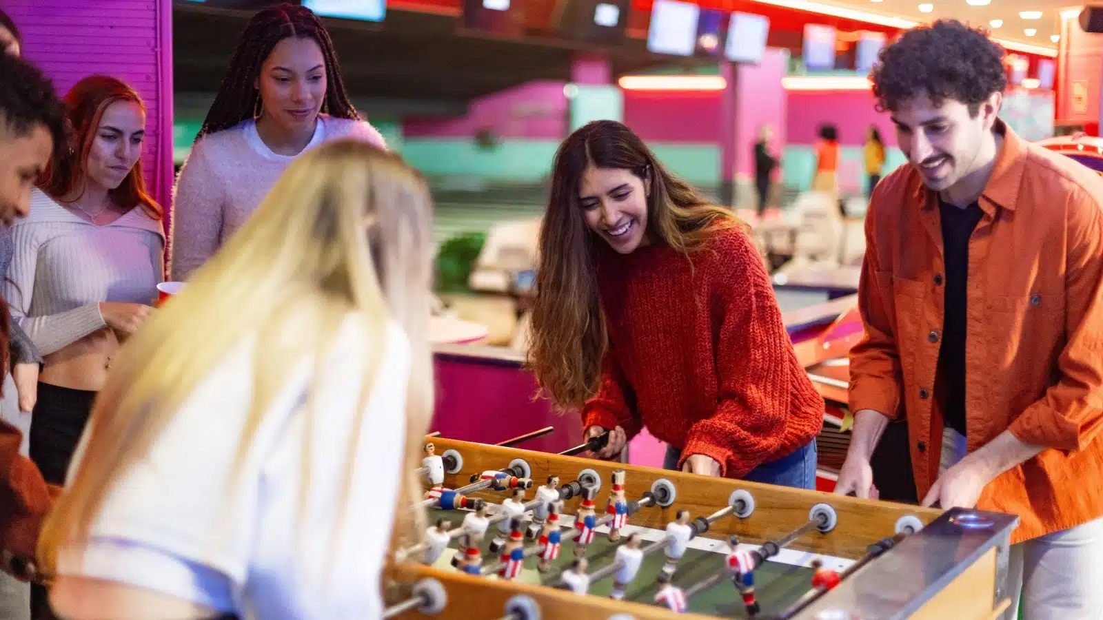 Friends playing foosball at a bar.