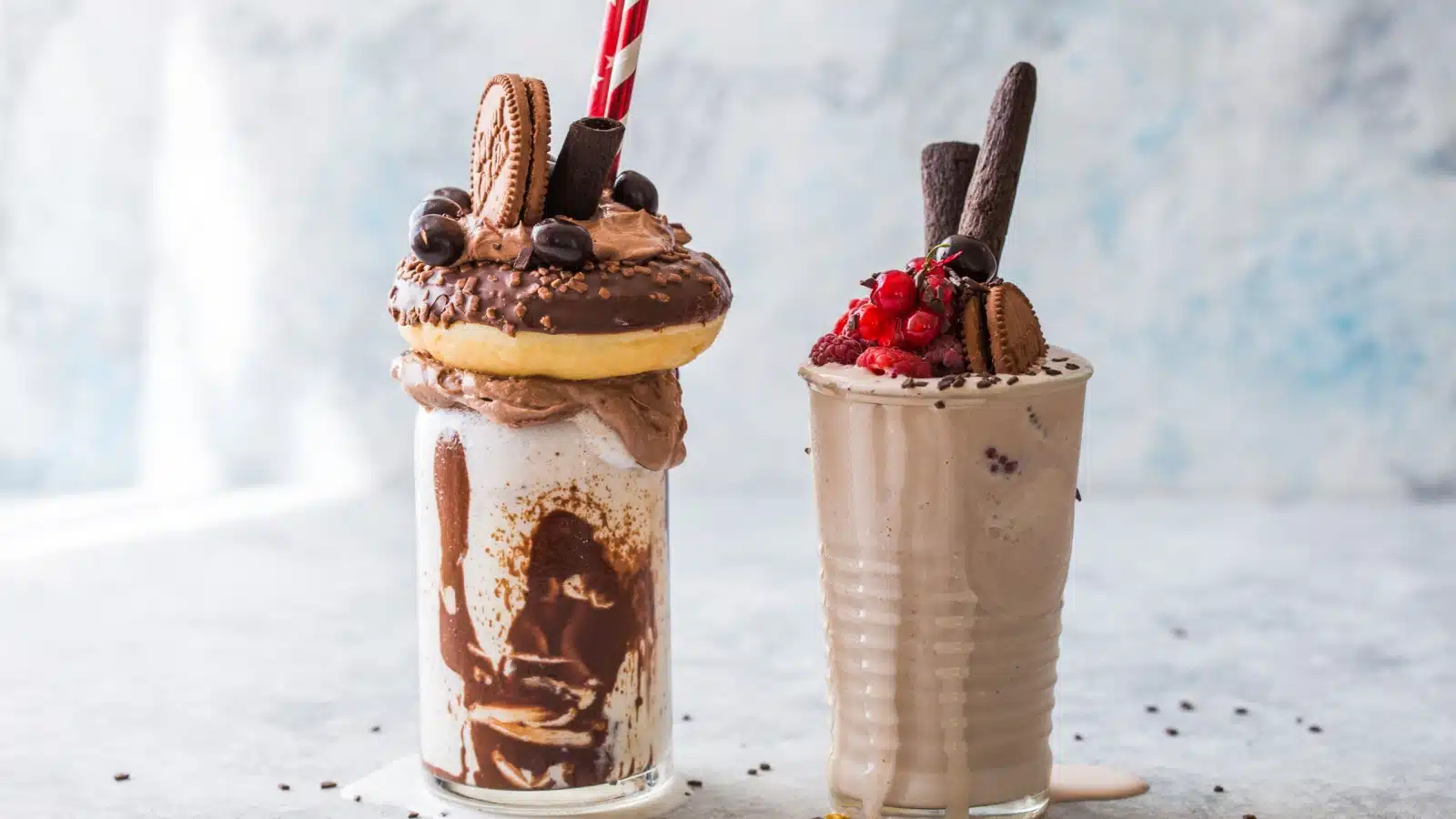 Two indulgent chocolate milkshakes - one of them is topped with a donut.