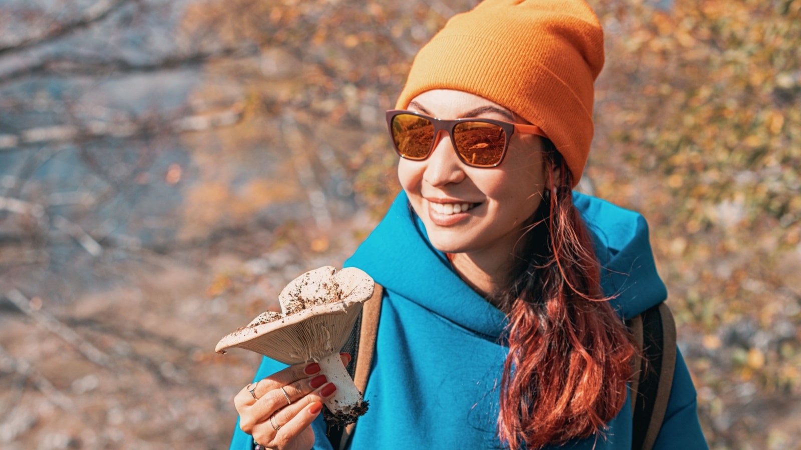 A woman holds a mushroom she foraged.