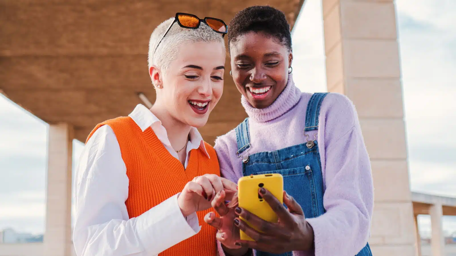 Friends looking at a phone together smiling.