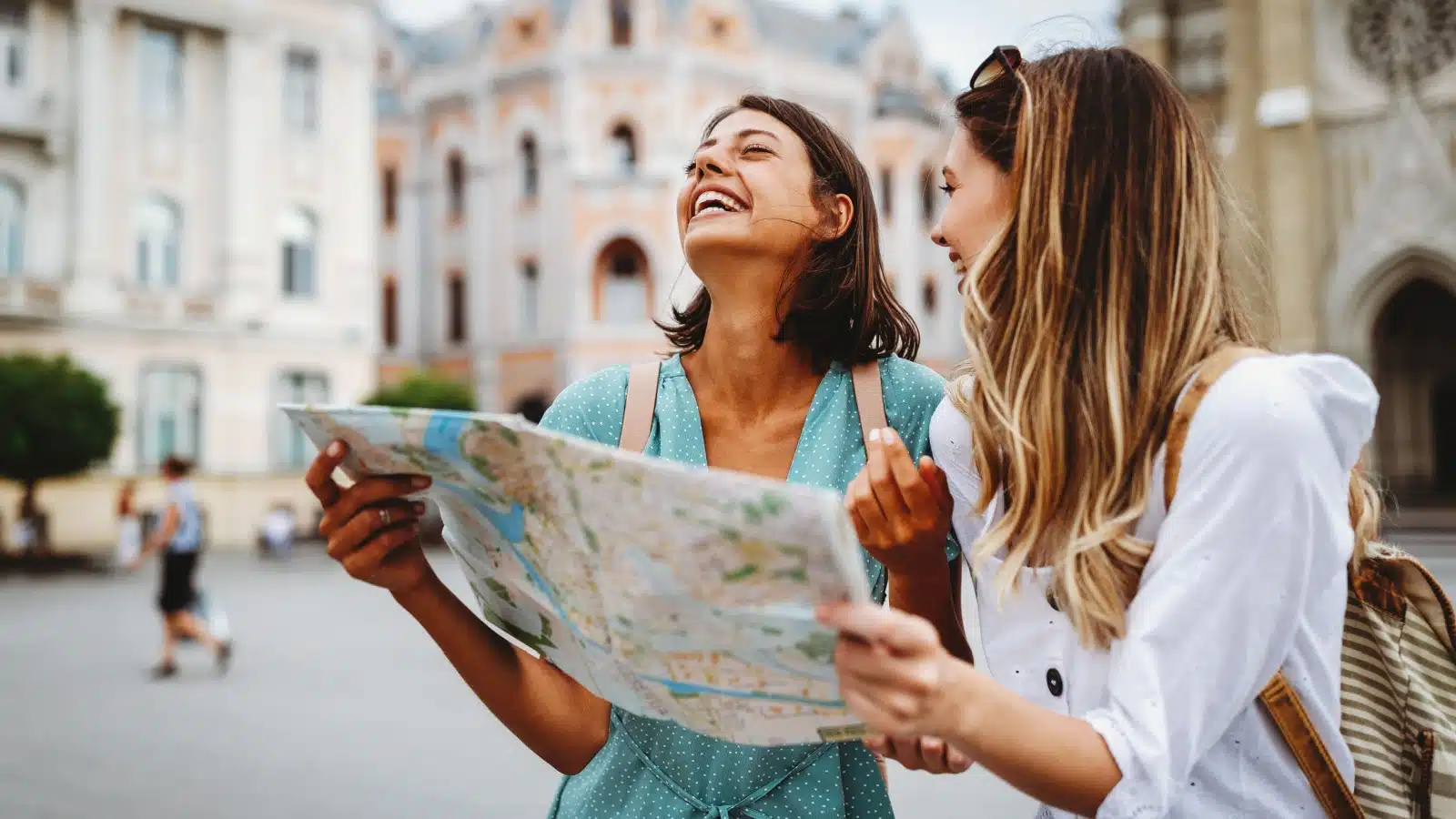Friends laughing while looking at a map during a girl's trip.
