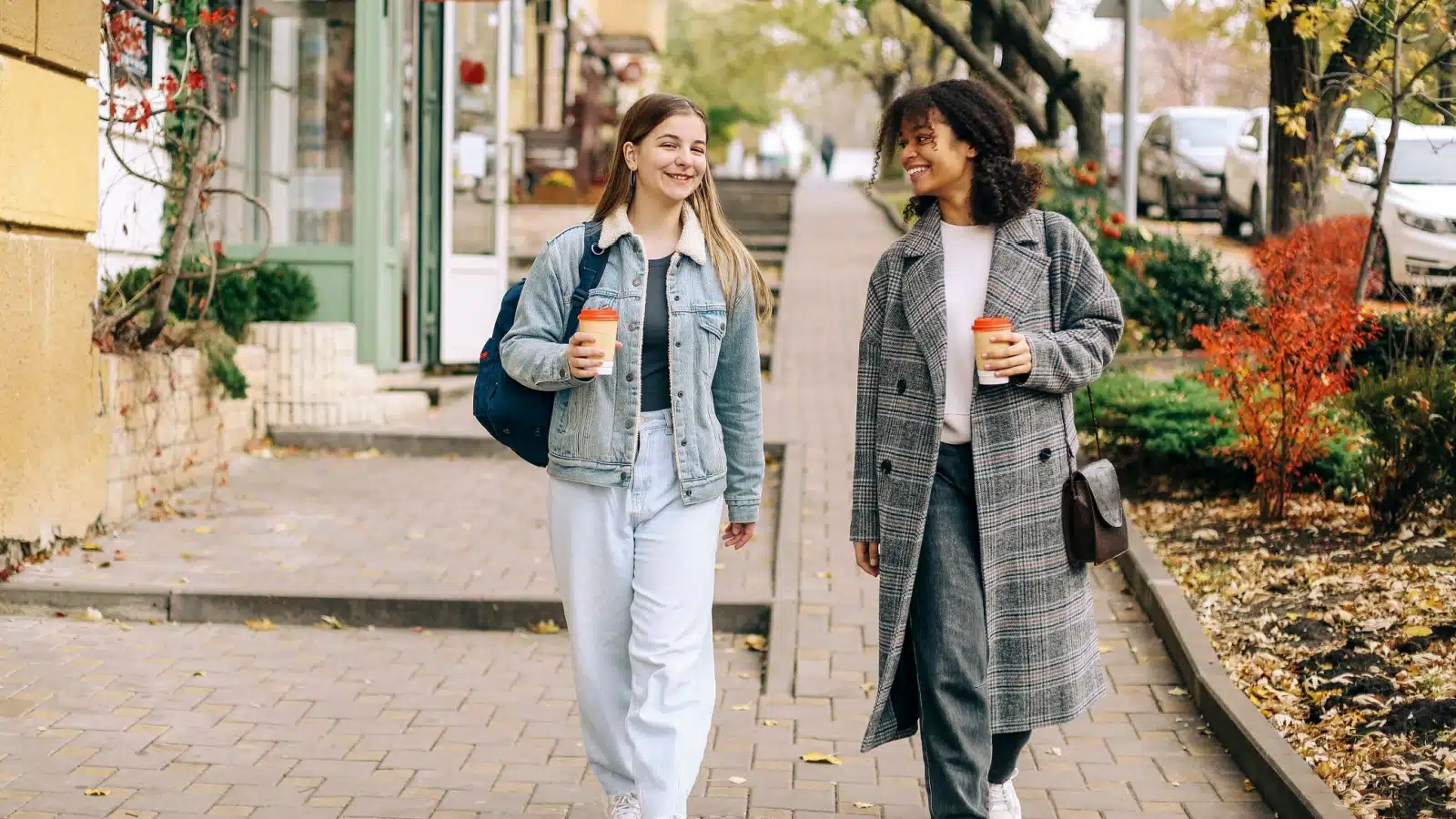 Two friends chat as they walk down the street.