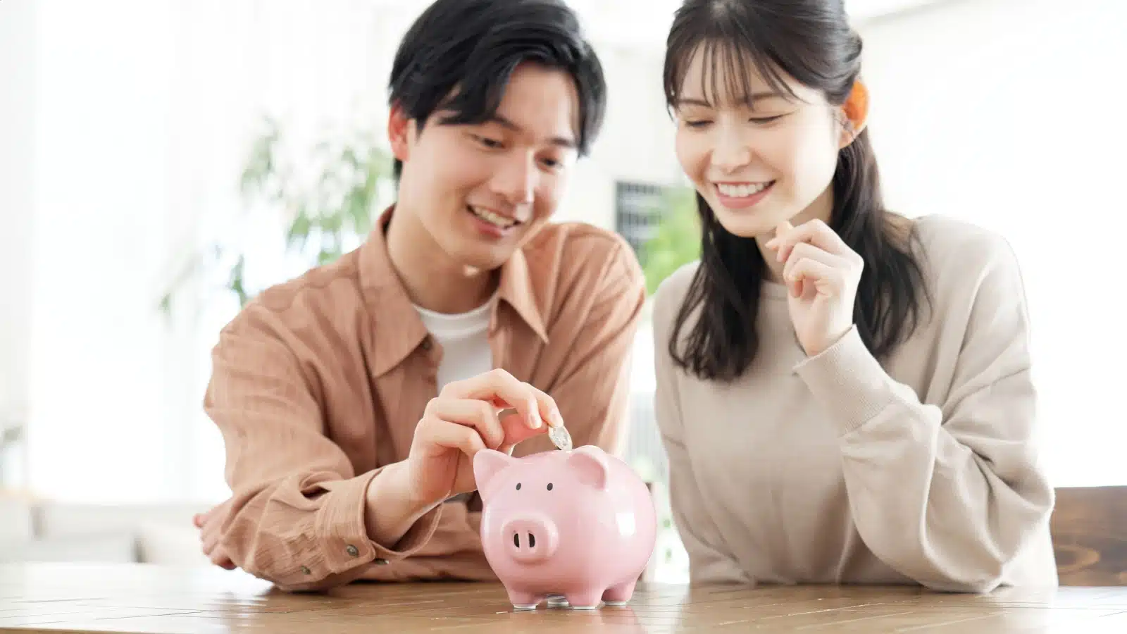 A couple putting coins in a piggy bank to represent frugal lifestyle tips.