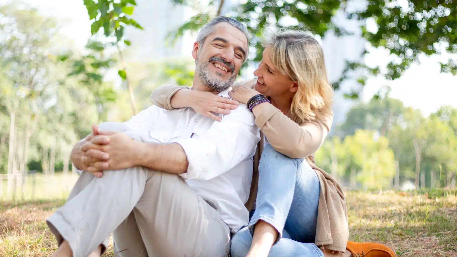 A happy senior couple sits in the grass enjoying life.
