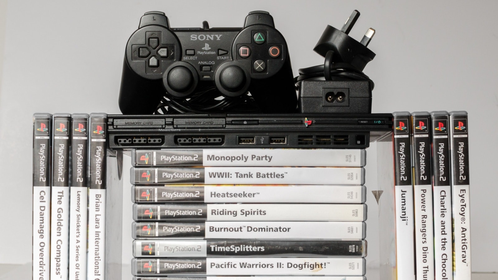 A PlayStation 2 controller sits atop a stack of games. TimeSplitter is near the bottom of the stack.