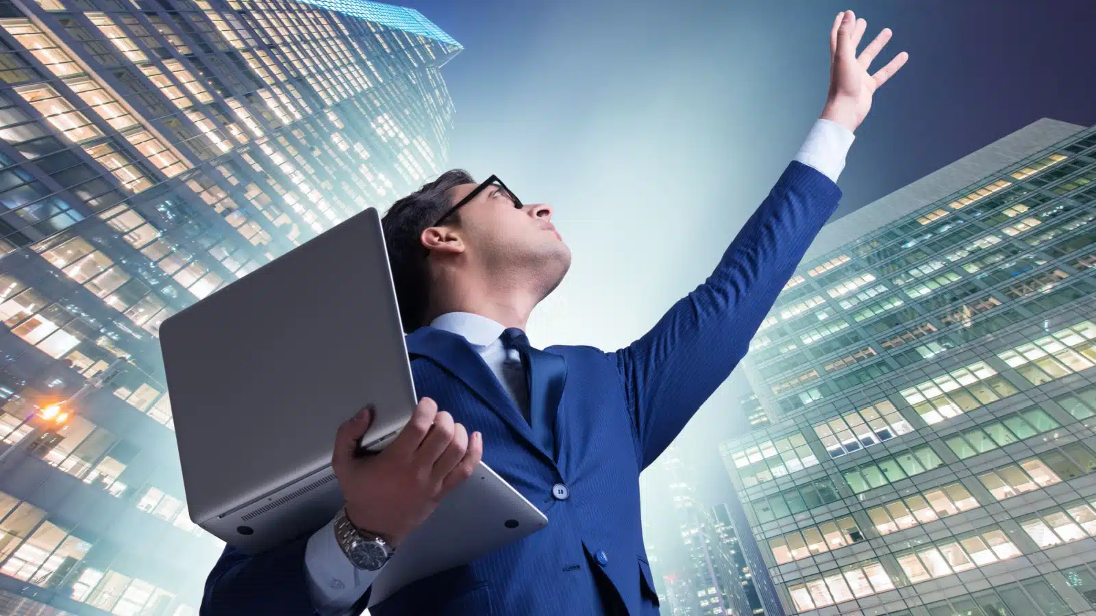 A businessman represents the balance between pragmatism and idealism. He stands on the ground holding his laptop while looking up and reaching for the sky.