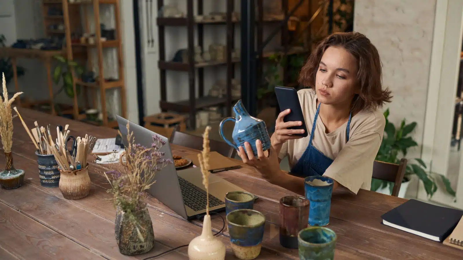 A woman takes a photo of pottery she created so she can sell it online.
