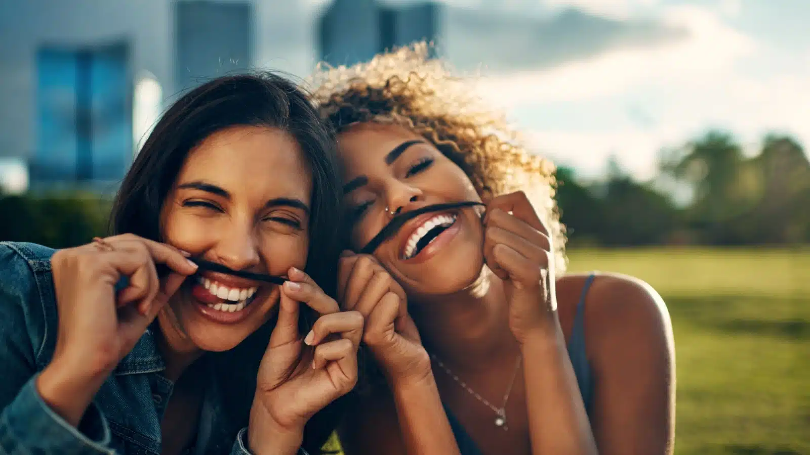 Two friends having silly fun by making fake mustaches out of their hair.