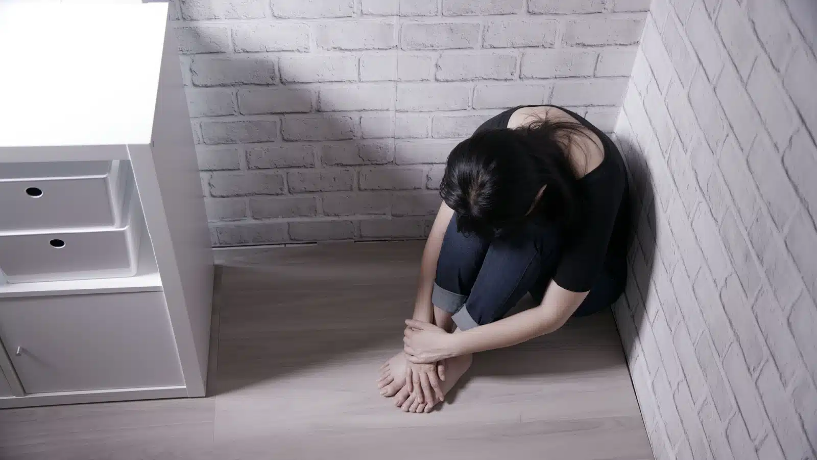 A sad lonely crouches in the corner, to represent taking up space while female. 