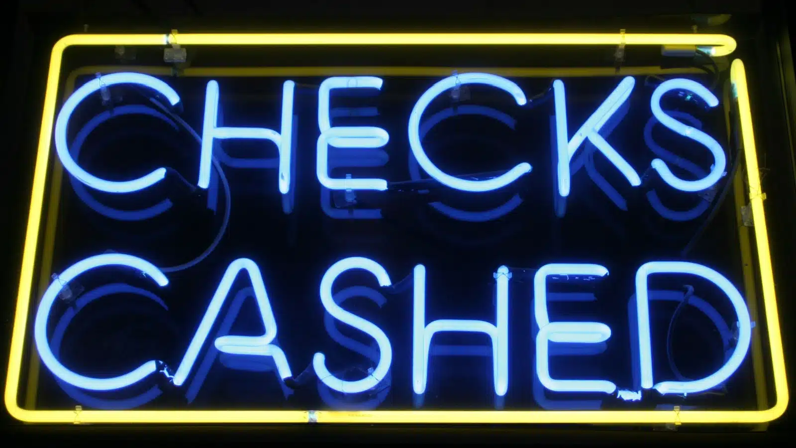 A neon sign says "checks cashed" for a check cashing service.
