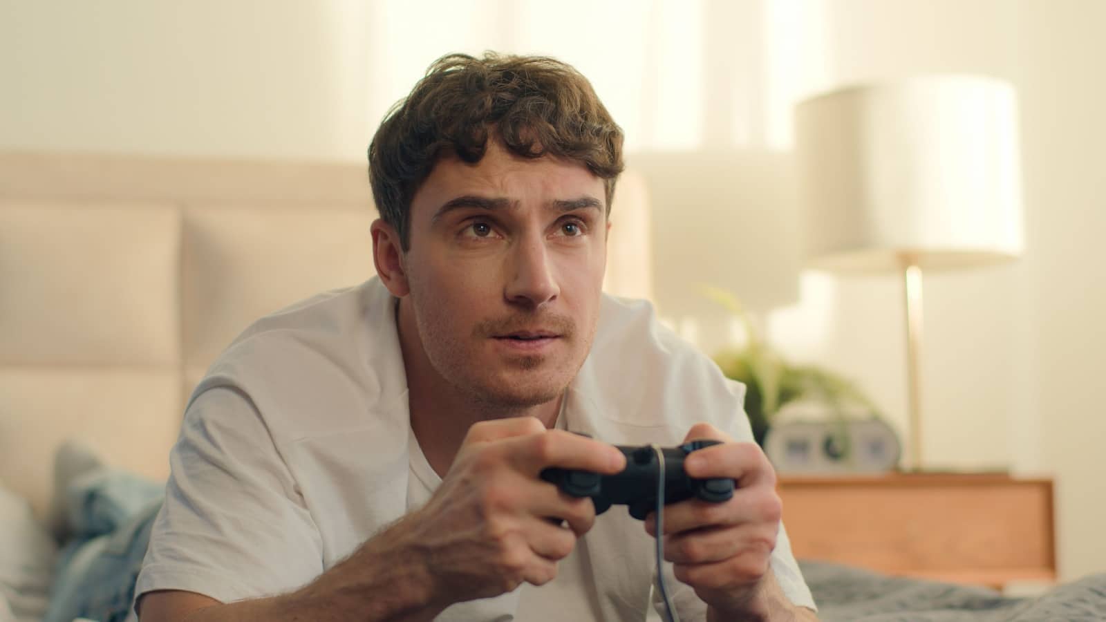 Close up of a man holding a controller, concentrating hard on his challenging video game.