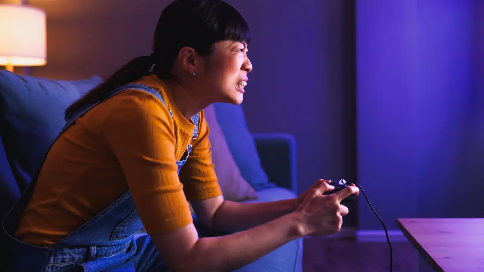A grimacing woman concentrating on the screen of a hard video game.