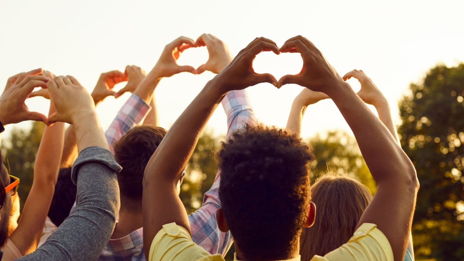A group of activists holding up heart signs with their friends to represent how to be a good person.