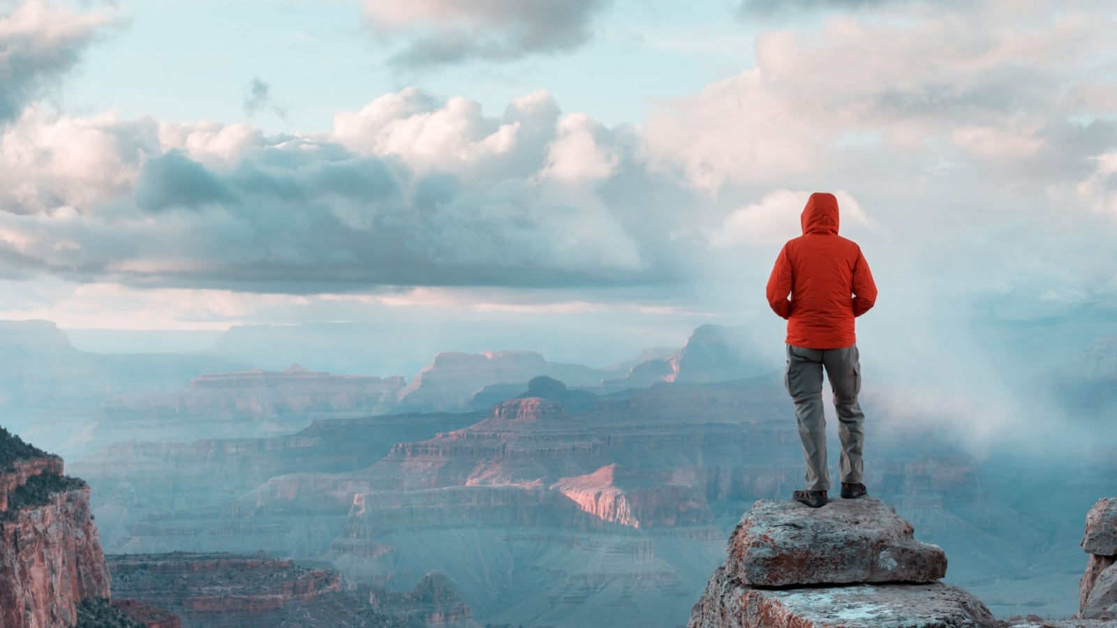 A hiker at the top of a mountain looking at a breathtaking view to represent inspirational quotes.