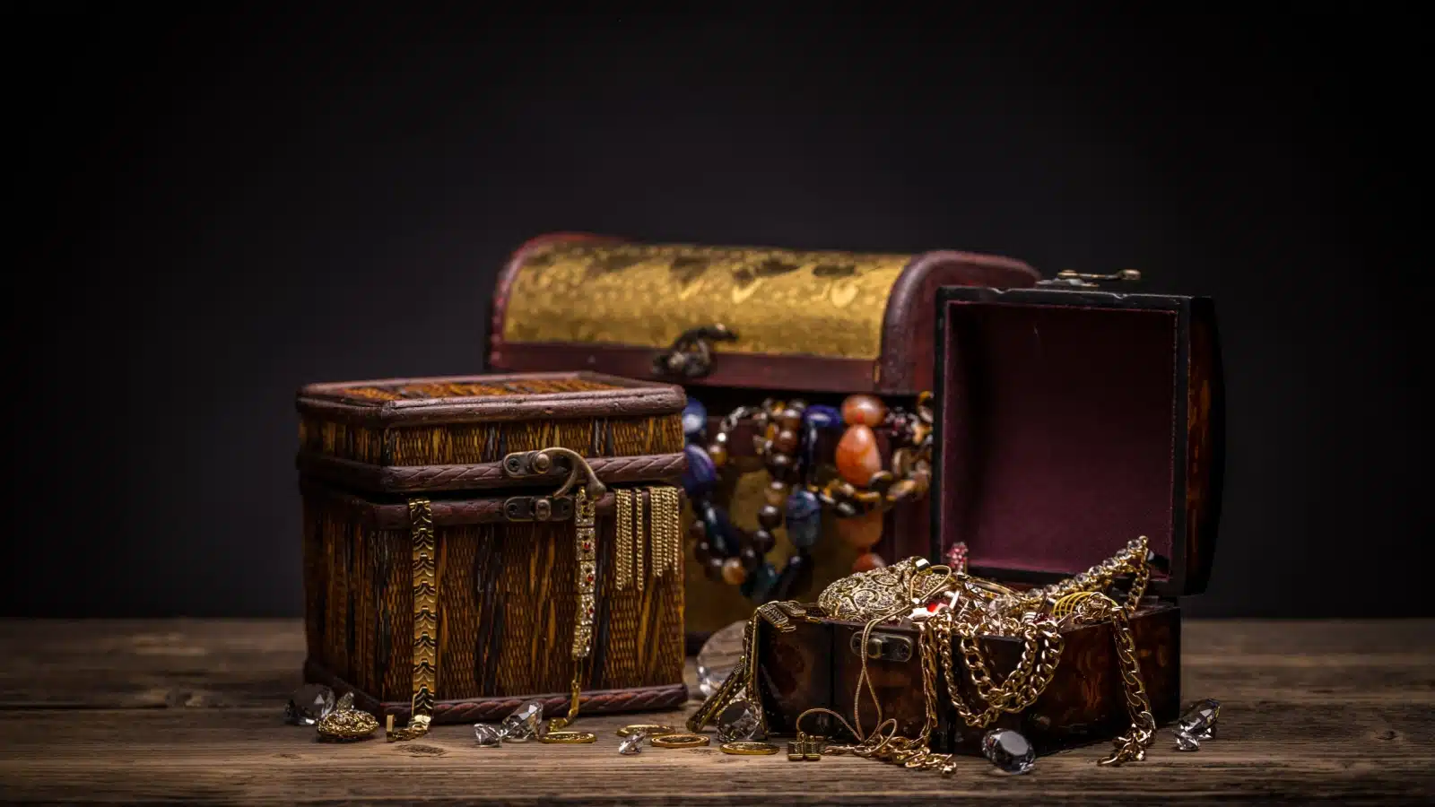 Old looking boxes with jewelry spilling out to represent historical treasures lost to time. 