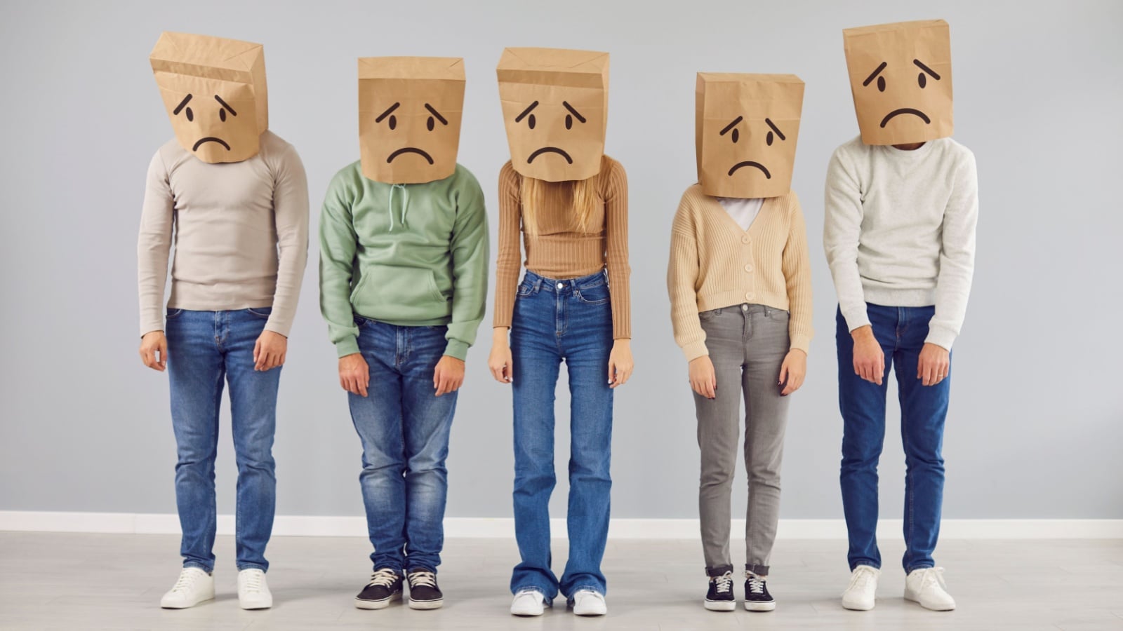 A line of slouched looking figures with sad faced paper bags over their faces to represent poverty shaming.