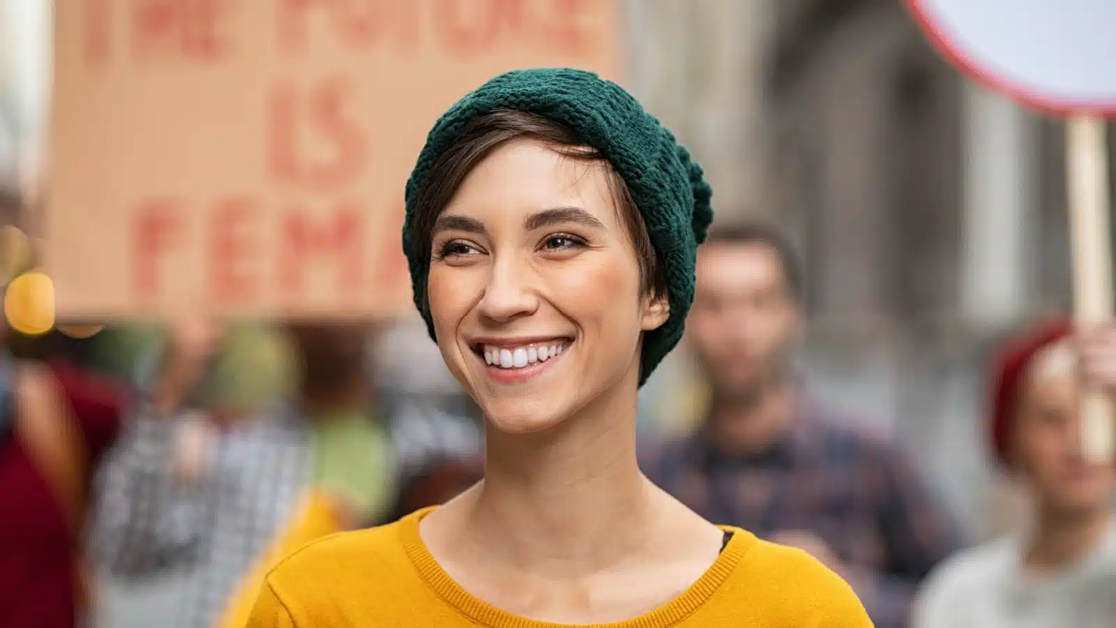 A smiling Millennial at a protest, happy that she's helped impact the world.