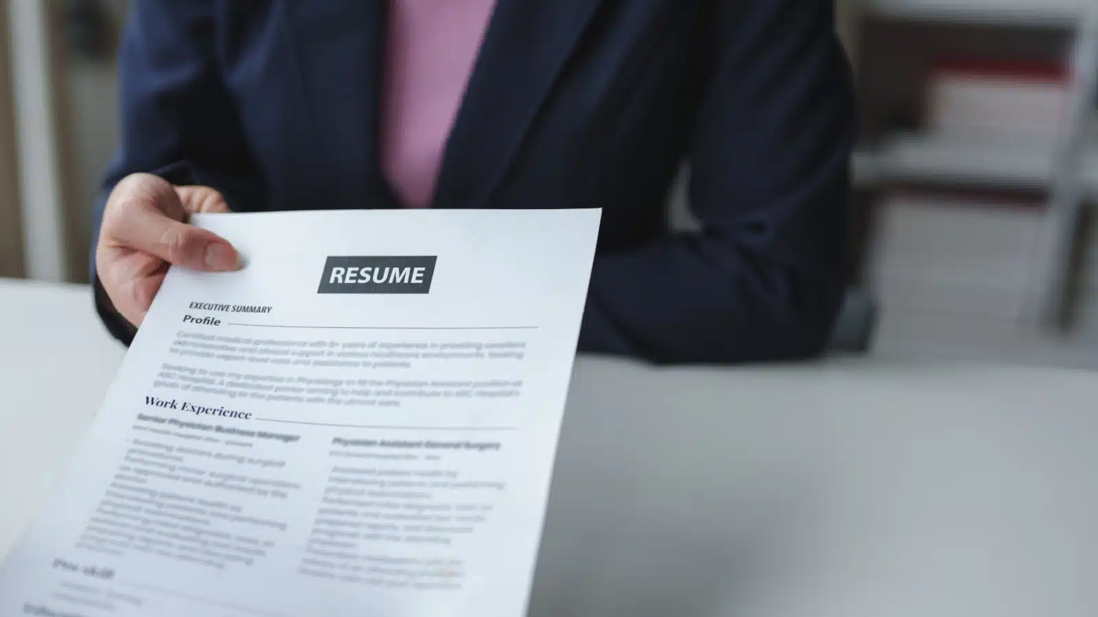 A candidate hands a resume to a hiring official to represent AI resume rejection. 