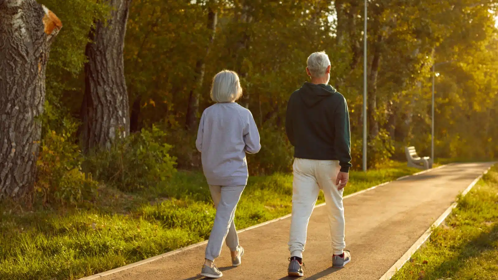 A senior couple on a well traveled life walk briskly in the morning.