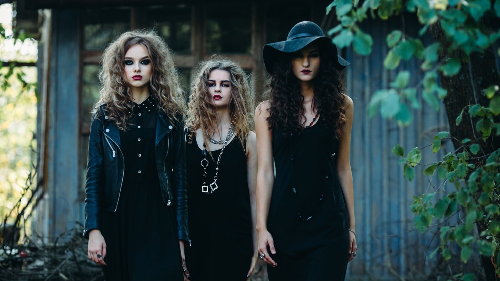 Three young women dressed in black modeling the public perception of a modern witch to represent the question are witches real.