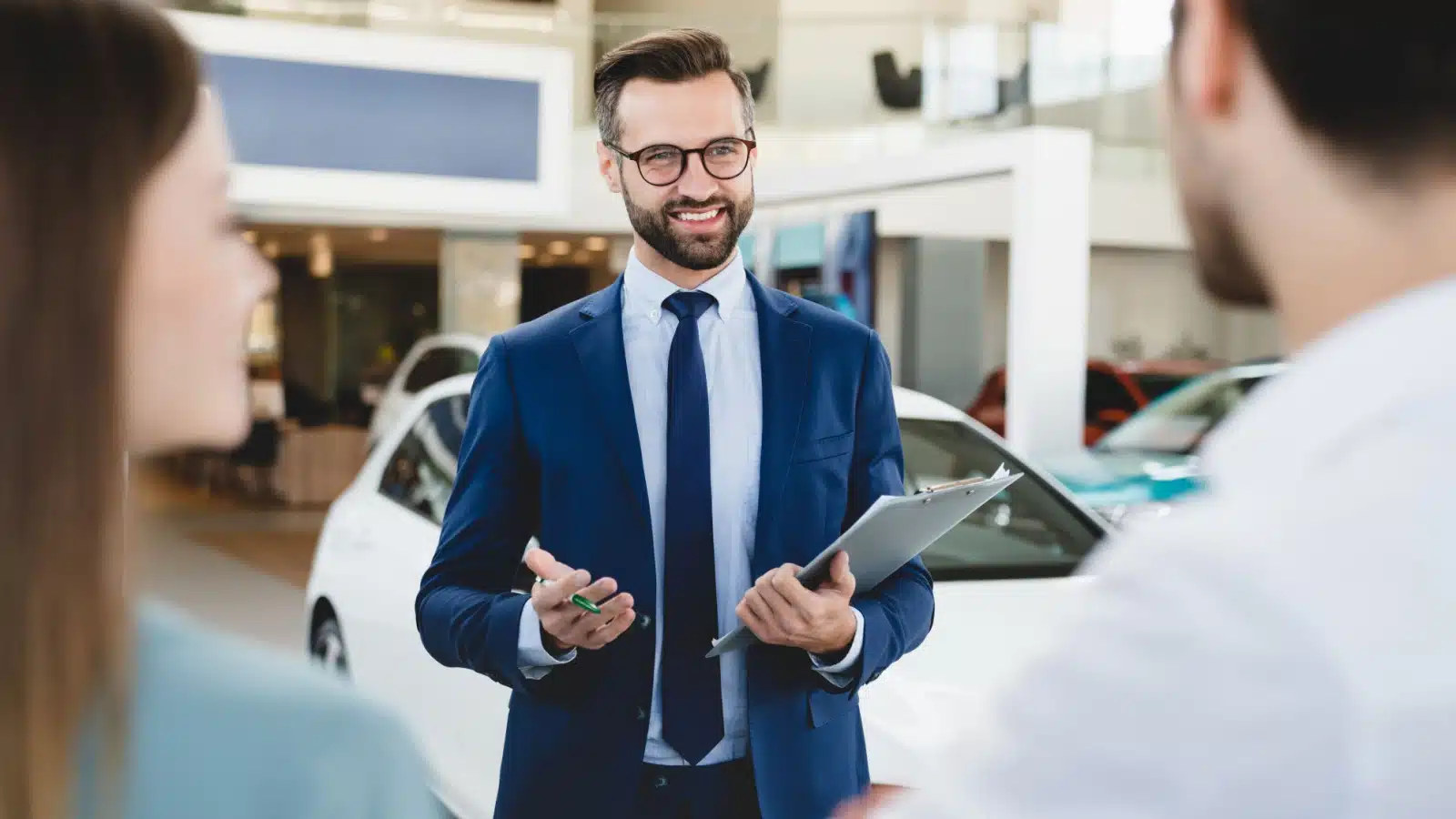 A car salesman focused on the man in a couple.
