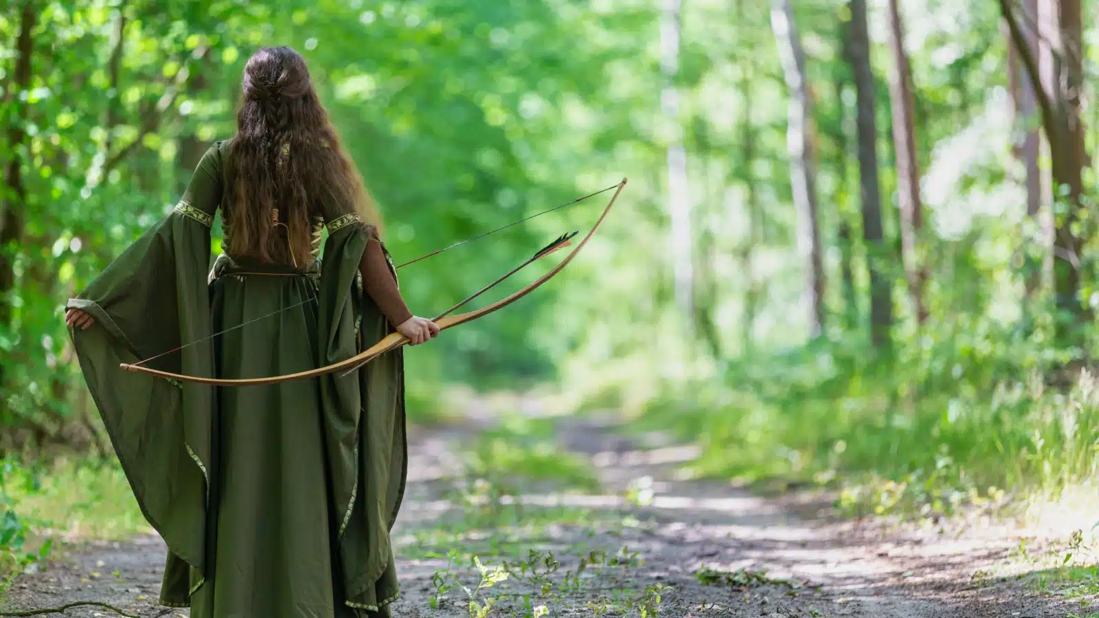 An elf archer holding her bow. The image shows the elf from behind, dressed in a long green cloak.