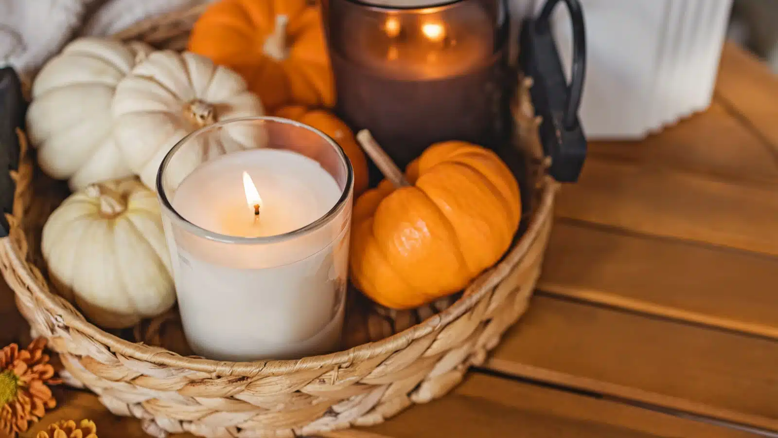 A basket with candles and mini pumpkins inside to represent the best fall scented candles.