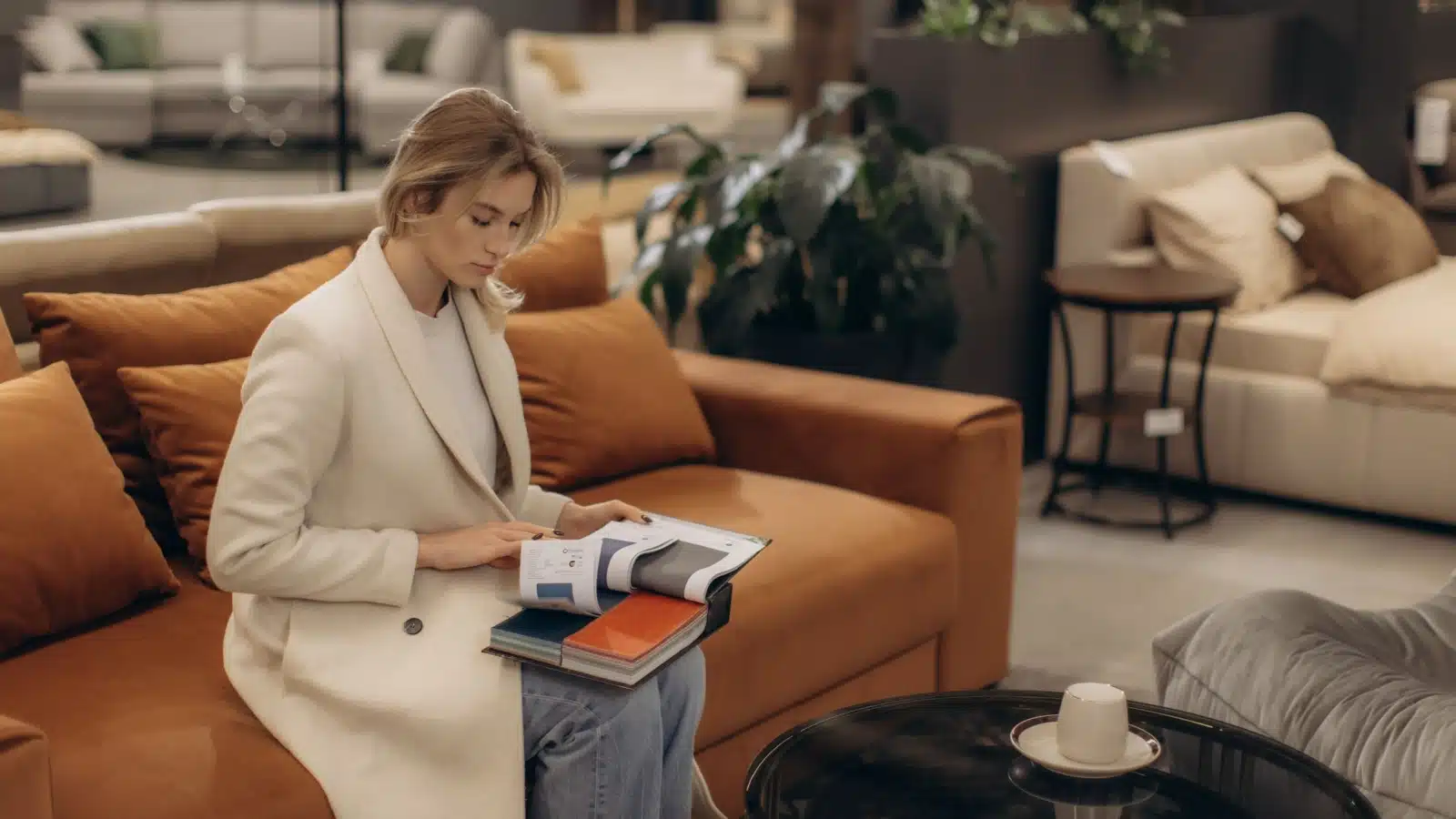 A woman flips through a catalogue while couch shopping at a furniture store.