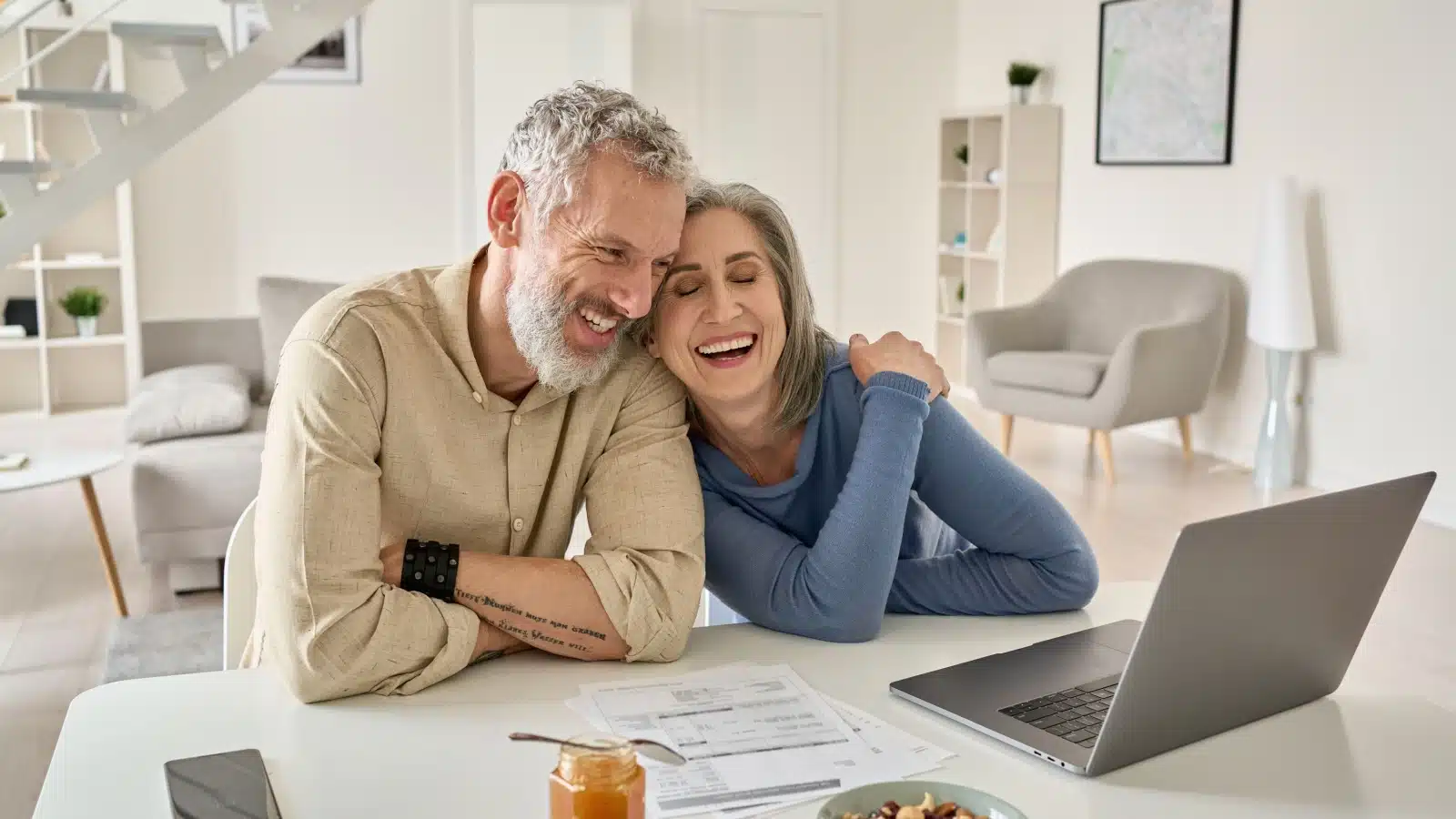 A happy couple reviews their financial statements on a computer.