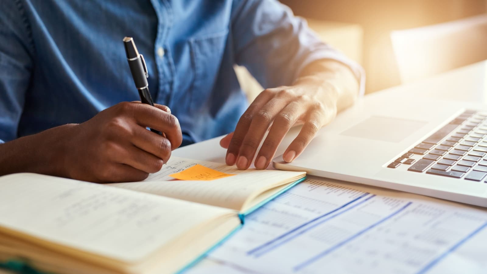 A man writes in his journal while working to brain dump, boosting his productivity.