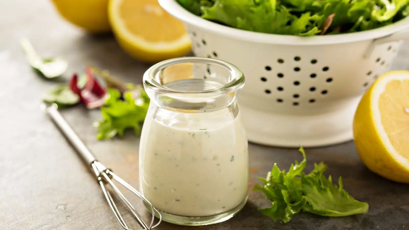 A bottle of homemade ranch dressing next to a salad.