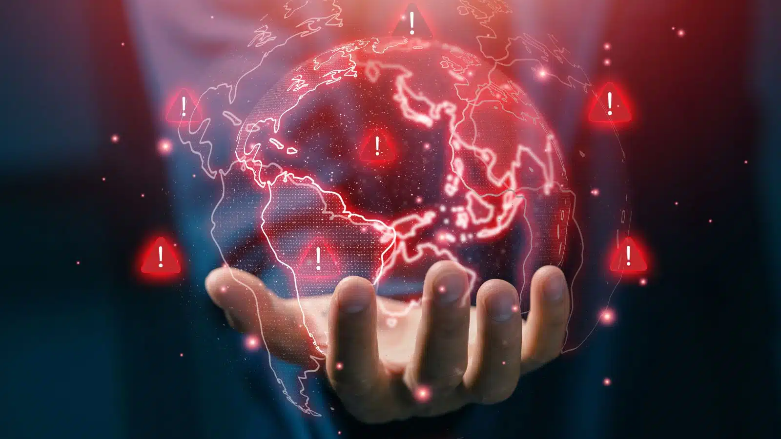 A man holds a globe outlined in red with red warning signs in various places to represent the biggest problems in the world.