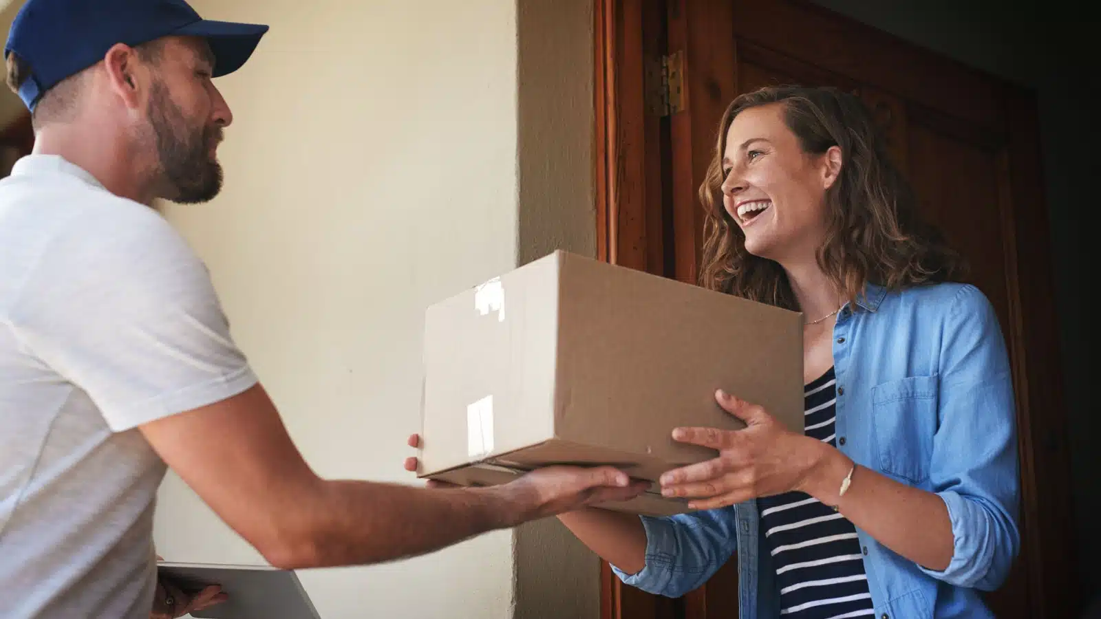 A woman receives a delivery at her door.