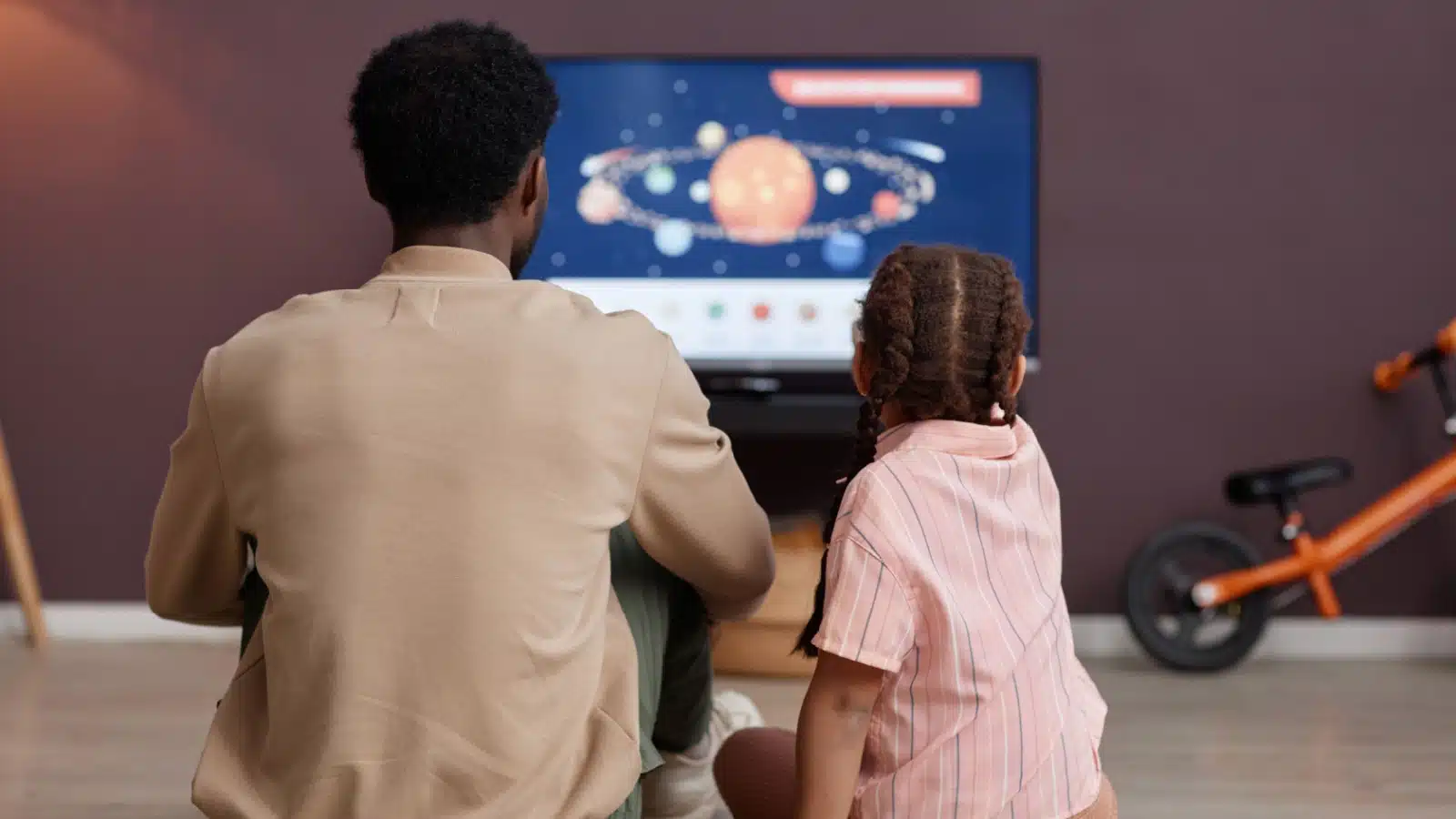 A father and daughter watch an educational show together.