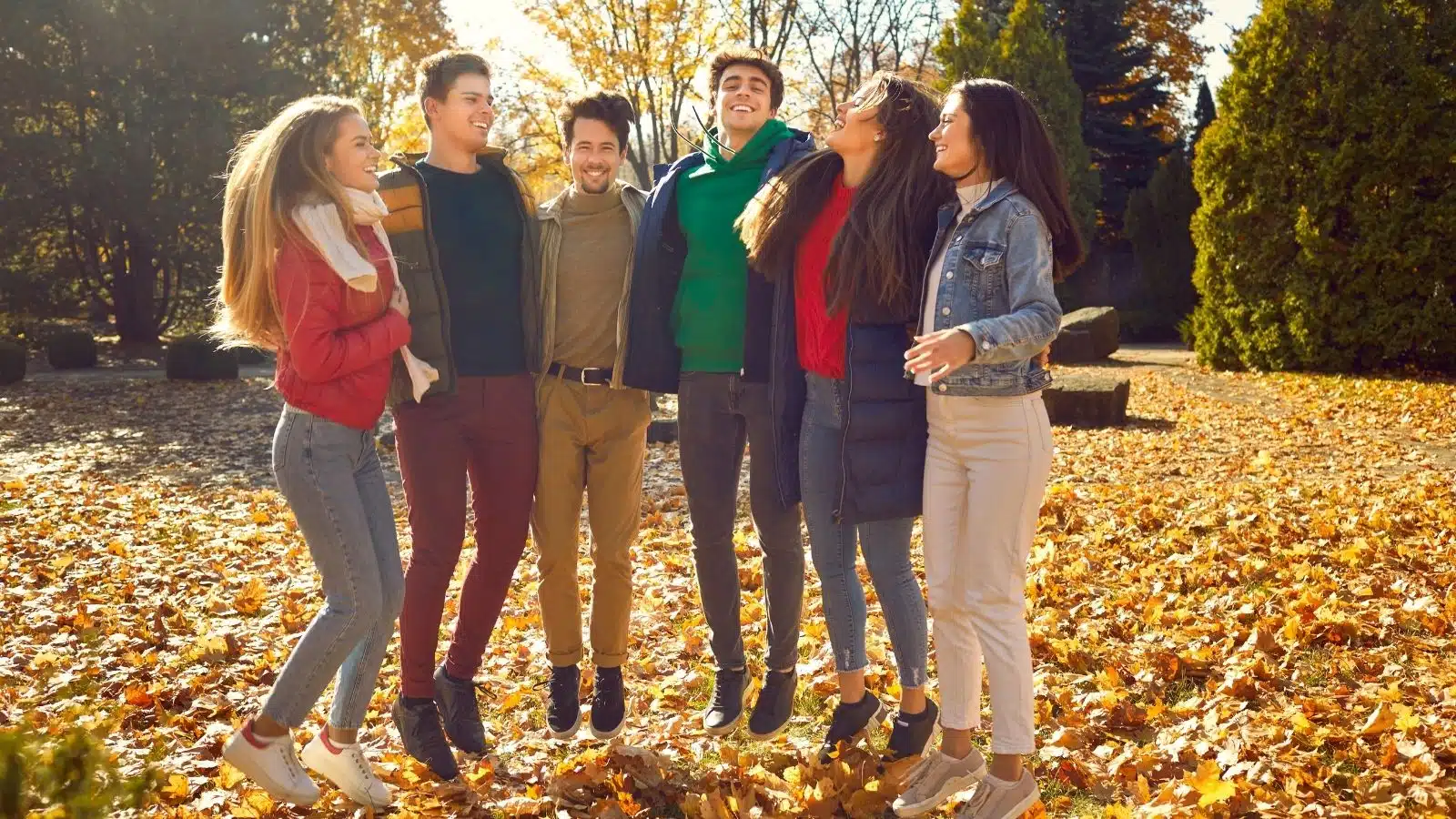 A group of friends hanging out in a park in autumn to represent fall fun on a budget.
