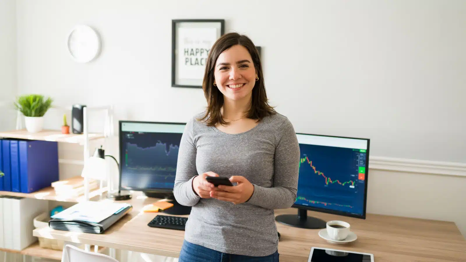 A young woman stands in front of monitors showing investment graphs, to represent investing for beginners.