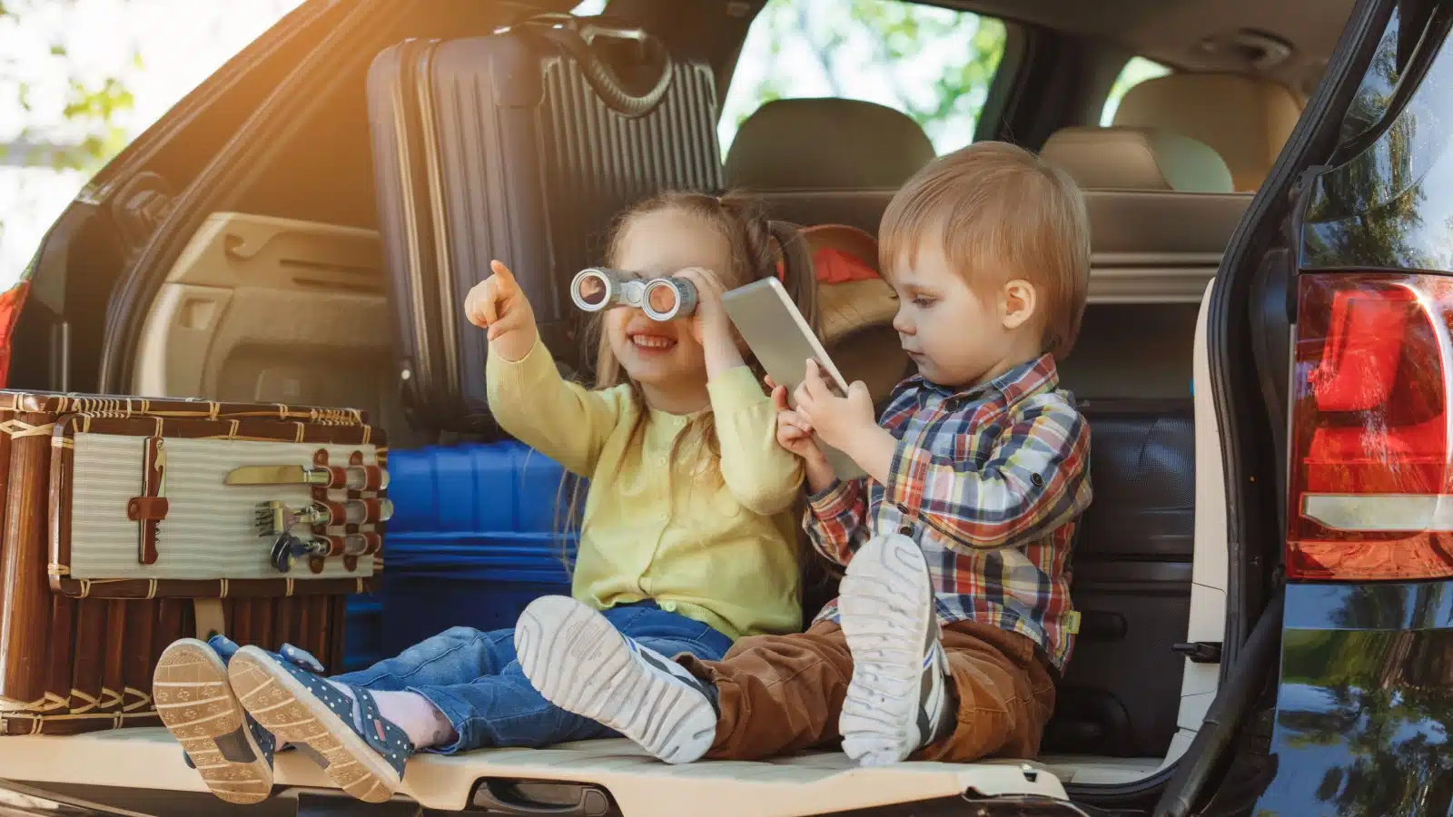Children in the back of a family car during a road trip break playing with toy binoculars.