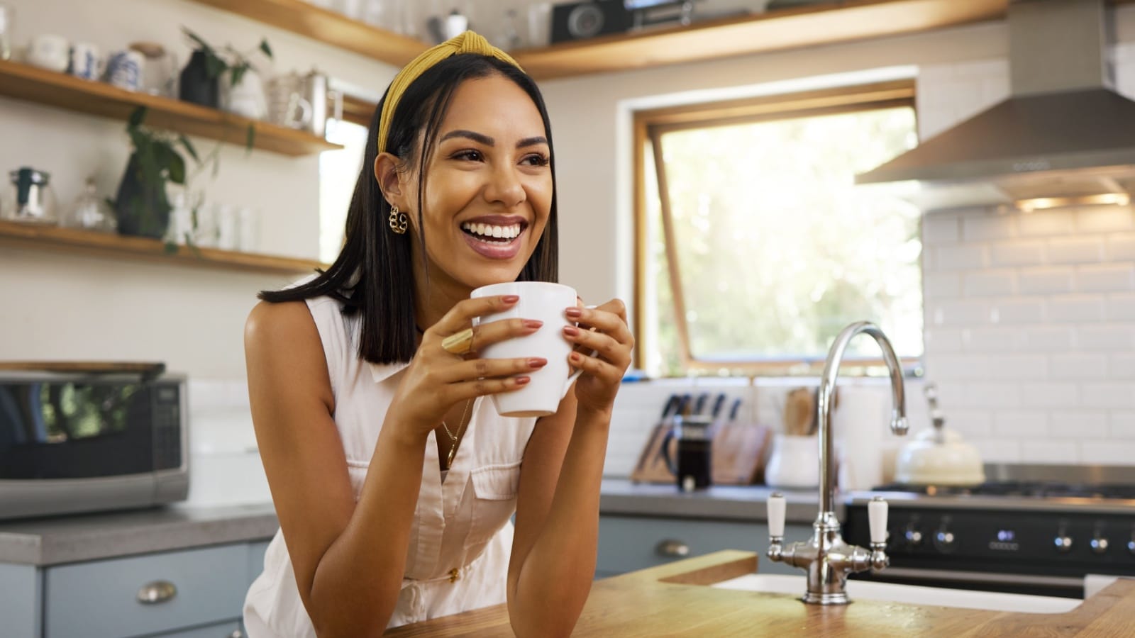 A woman smiles as she enjoys her morning coffee to represent productive habits.