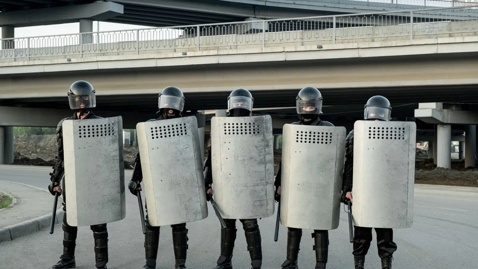 A line of riot police with metal shields and batons. 